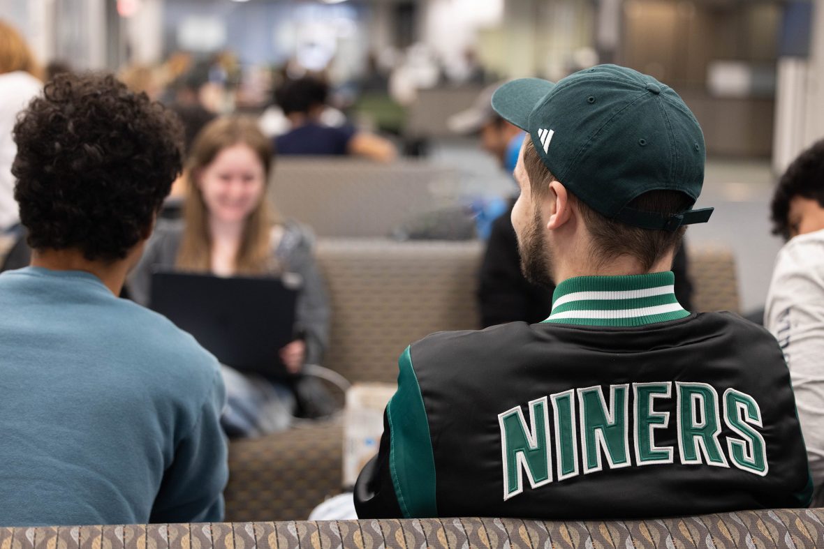 Person in a “Niners” jacket talking with others in a lounge.